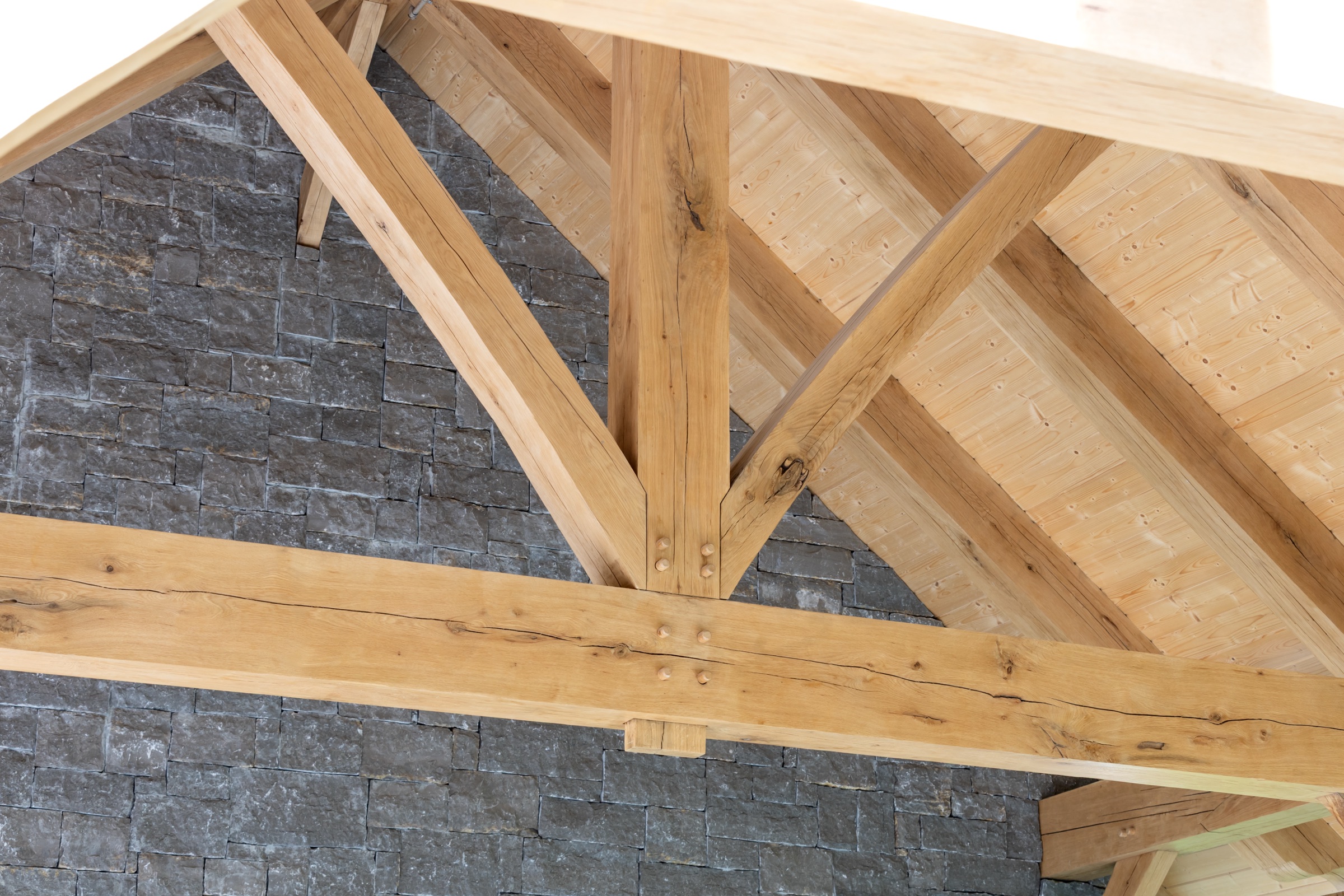 King post timber truss against a gray stone wall