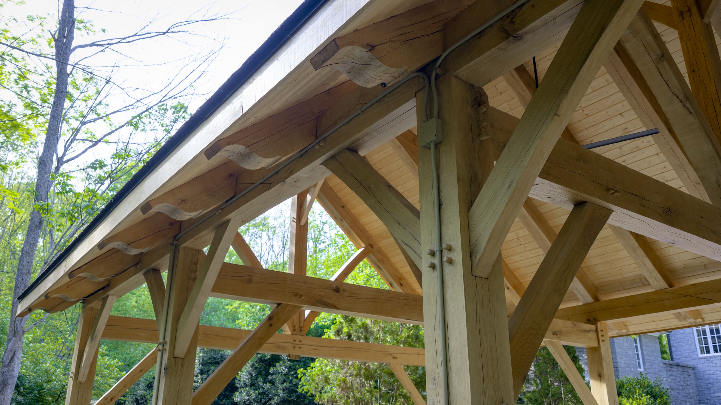 Timber frame gable end with gray stone back wall under construction